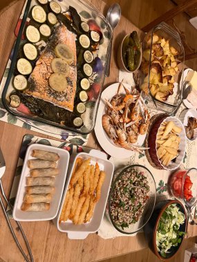 Noel sofrasında aile ziyafeti soğuk büfe lezzetli balık yemekleri kabak limon somon balığı karides kuyruk salata salata ve turşu peynirli bisküvi 
