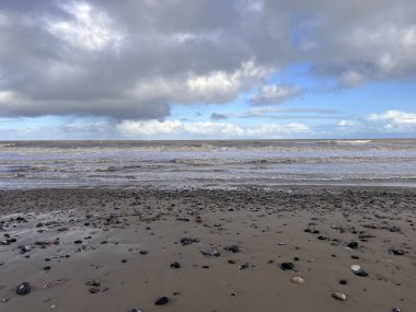 Manzara dramatik kumlu sahil kıyısı okyanus ufkunda bulutlu güzel kış günü sörf dalgaları yüksek rüzgar ve dramatik mavi yuvarlanan bulut kışın Norfolk East Anglia uk