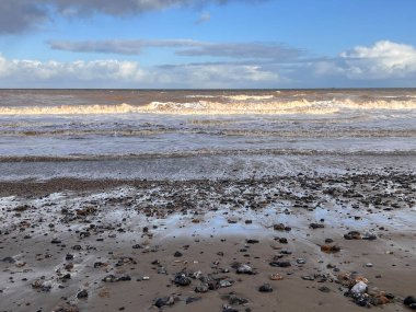 Manzara dramatik kumlu sahil kıyısı okyanus ufkunda bulutlu güzel kış günü sörf dalgaları yüksek rüzgar ve dramatik mavi yuvarlanan bulut kışın Norfolk East Anglia uk