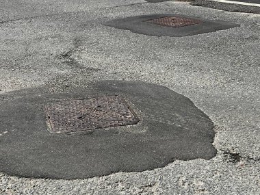 Tamamlanmamış yolun kapanışı sert gri asfalt yüzeyi çakıl taşı çatlakları ve metal drenaj kapağı ile işliyor. Yoldan çıkan çıkıntılar ve hanedanlığın kaldırımları düz değil. Beyaz çizgili işaretleri olan kimse yok.