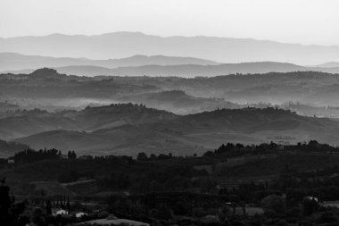 Sabahın erken saatlerinde İtalya 'nın Montaione kenti yakınlarında tepeleri ve selvileri olan tipik Toskana manzarası.