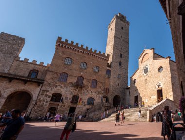 SAN GIMIGNANO, ITALY - 20 Eylül 2023 - San Gimignano 'daki ana meydan Piazza del Duomo ünlü saray kuleleri, Palazzo Comunale' in büyük kulesi ve İtalya 'nın merkezindeki katedral