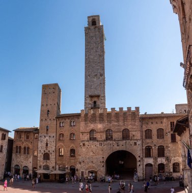 SAN GIMIGNANO, ITALY - 20 SEPTEMBER 2023 - San Gimignano 'daki ana meydan Piazza del Duomo, merkezinde ünlü saray kuleleri, Rognosa kulesi ve Theater dei Leggieri ile, İtalya