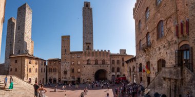 SAN GIMIGNANO, ITALY - 20 SEPTEMBER 2023 - San Gimignano 'daki ana meydan Piazza del Duomo, merkezinde ünlü saray kuleleri, Rognosa kulesi ve Theater dei Leggieri ile, İtalya