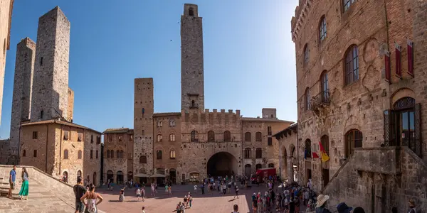 SAN GIMIGNANO, ITALY - 20 SEPTEMBER 2023 - San Gimignano 'daki ana meydan Piazza del Duomo, merkezinde ünlü saray kuleleri, Rognosa kulesi ve Theater dei Leggieri ile, İtalya