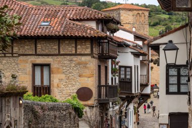 Kuzey İspanya 'nın Cantabria bölgesindeki Santillana del Mar kasabasında antik evler ve taş bir duvarla çevrili bir kaldırım taşı caddesindeki turistler