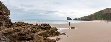 People walking at the tranquil Torimbia beach at the Asturian coast in Northern Spain clipart