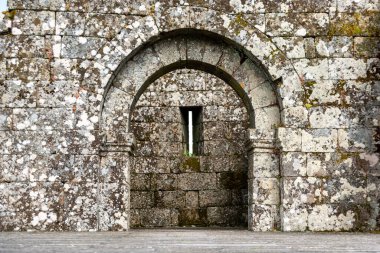 Portekiz 'in Tracoso kentindeki ortaçağ şatosunda delikleri olan manzaralı kemerli bir kapı.