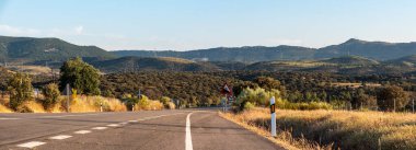 İspanya 'nın Extramadura bölgesinin kırsal manzarasına giden bir otoyolda gün batımı.