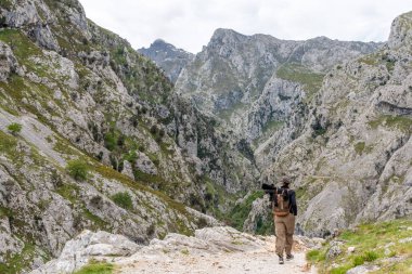 Resimli yürüyüşlere çıkan bir kadın turist Kuzey İspanya 'daki Asturias Picos de Europa dağlarındaki vadiyi önemsiyor.