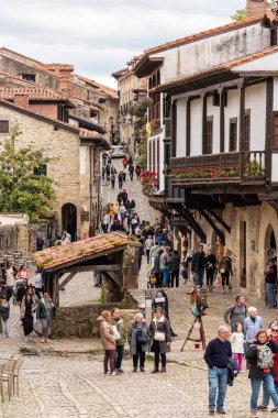 Santillana del Mar, İspanya - Mai 18, 2024 - Kuzey İspanya 'nın Santillana del Mar kasabasında antik evler ve taş bir duvarla çevrili bir kaldırım taşı caddesindeki turistler
