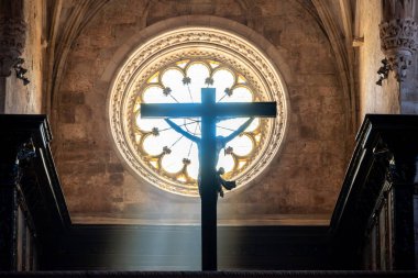 Ortaçağ kilisesinde çarmıha gerilen İsa 'nın yuvarlak penceresinden parlayan güneş.