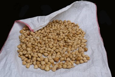 Plastik beyaz muşamba ve siyah arkaplanda kurumuş nohut yığını