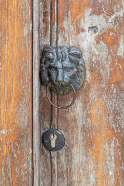 Antique patina brass lion head door knocker and keyhole on old wooden door panel. Copy space