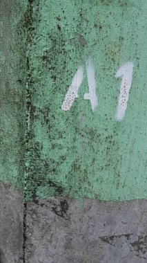 Distressed metal with long seam on side and black mildew stains with white letter and number