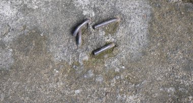 Concrete pavement sewer cover with three steel bent nails in Bali, Indonesia