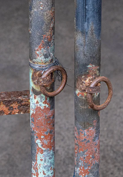 Two isolated rusted steel pipes with metal rings soldered onto them