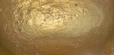 Close up of gold painted concrete with chipping and cracks. Highlighted in center