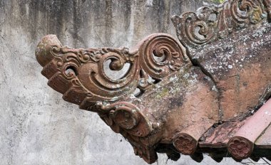 Bali evinin çatısının kenarındaki terracotta parşömen tasarımını kapat. Siyah lekeli beton duvar. Boşluğu kopyala