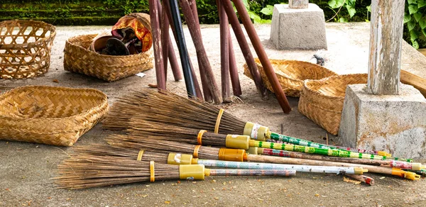 Renkli saplı Balili süpürge yığını arka planda sepet sunumlarıyla beton levha üzerinde yatıyordu.