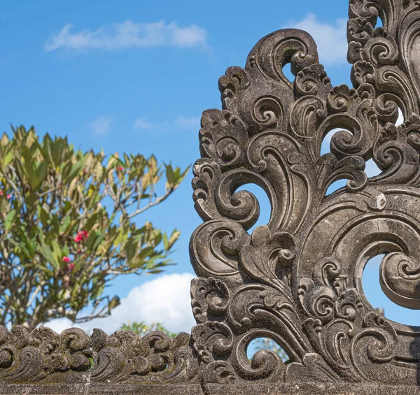 Bali Tapınağı 'nın köşesindeki beton parşömen tasarımını kapat. Çatı, tropik bitki ve mavi gökyüzü. Arka planda küçük bulutlar.