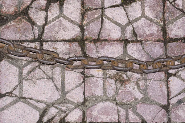肮脏的粉红色马赛克石制路面 上面铺有锈蚀的厚金属链 — 图库照片