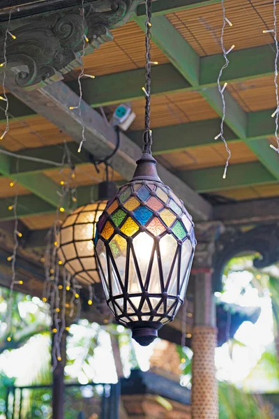 Stained glass light fixtures hanging from wood beams and blurred background