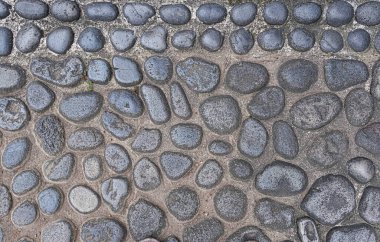 Beton zemin ve duvar kağıdı dokusunda çeşitli büyüklükte nehir taşları.