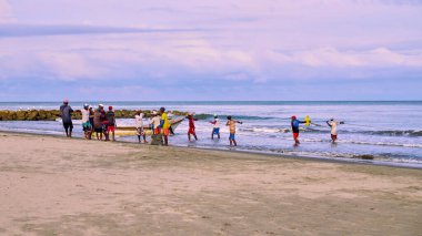 Cartagena, Bolivar Kolombiya - 1 Şubat 2024: Tramvayda yakalanan balıkları toplamak için Cartagena sahilindeki ağları toplayan bir grup balıkçı.