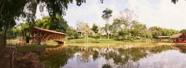 Tropikal Sahne; Bambu Köprüsü ve Thatched-Roof Hut ile Lagoon. Tanınmayan insanlar            