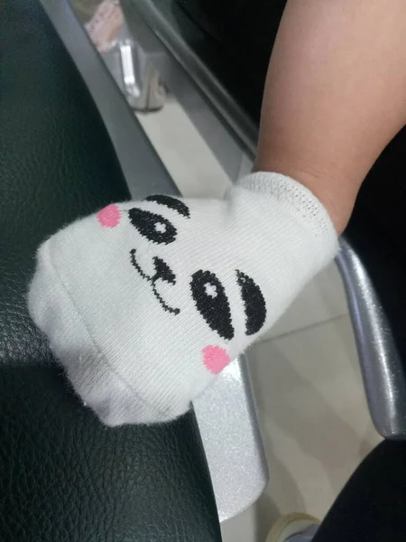 かわいいパンダの顔をした靴下の中の赤ちゃんの足の写真 — ストック写真