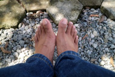 Bir çift erkek bacağının koyu kahverengi bir fotoğrafı. 30 yaşlarındaydı. çakıl arkaplanı