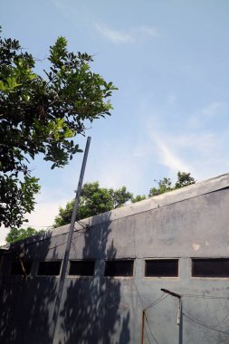 Birkaç havalandırması olan bir ev duvarı manzarası. Onun üzerinde gün boyunca parlak mavi bir gökyüzü var.