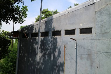 Birkaç havalandırması olan bir ev duvarı manzarası. Onun üzerinde gün boyunca parlak mavi bir gökyüzü var.