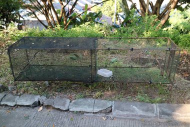 Bahçenin kenarında uzamış şekilli demir telden yapılmış bir kuş kafesinin fotoğrafı.