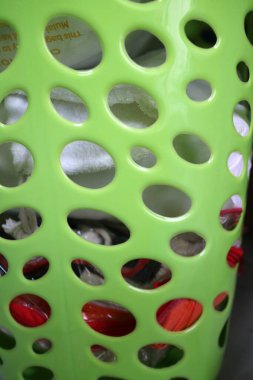 Giysi sepetinin yan tarafındaki fotoğraf açık yeşil plastikten yapılmış ve onu benzersiz yapan bir delik deseni var..