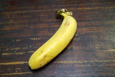 Olgun, sarı bir muzun fotoğrafı ahşap bir masaya konur.