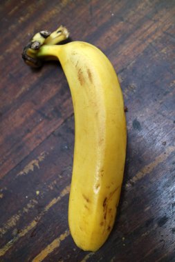 Olgun, sarı bir muzun fotoğrafı ahşap bir masaya konur.