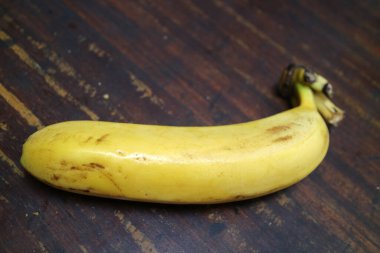 Olgun, sarı bir muzun fotoğrafı ahşap bir masaya konur.