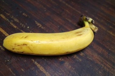 Olgun, sarı bir muzun fotoğrafı ahşap bir masaya konur.