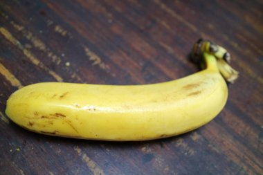 Olgun, sarı bir muzun fotoğrafı ahşap bir masaya konur.