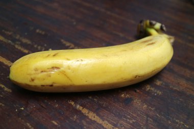 Olgun, sarı bir muzun fotoğrafı ahşap bir masaya konur.