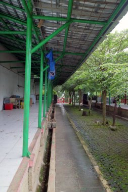 Yeşil çelikten çatı yapısı olan bir binanın yanındaki açık hava koridorunun fotoğrafı