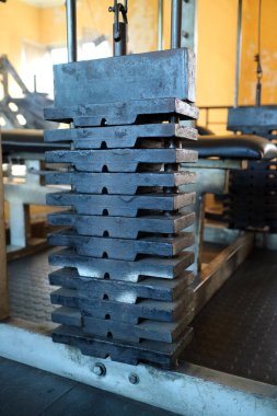 Spor salonundaki ağırlık plakalarının yakın çekim görüntüsü tabakaların dokusunu ve yapısını gözler önüne seriyor. Arka planda spor aletleri ve turuncu bir duvar var..