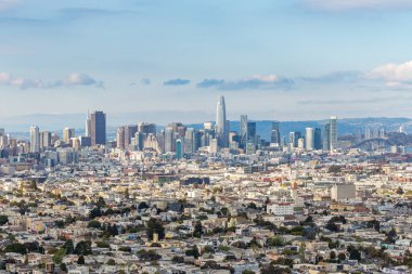 San Francisco şehrinin gökyüzü güneşli ve güzel bir günde ön planda evleri ve arka planda şehirleri var..