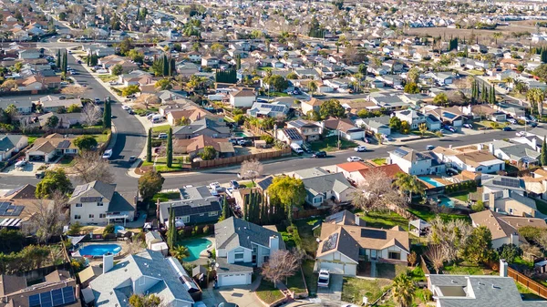 Drone photos over a community in California with houses, streets and cars.