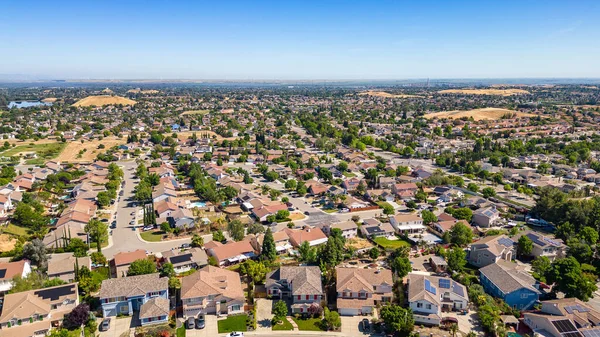 stock image A breathtaking aerial view of Antioch, California: houses nestled amidst verdant hills, crisscrossed by meandering streets, all under a picturesque blue sky.