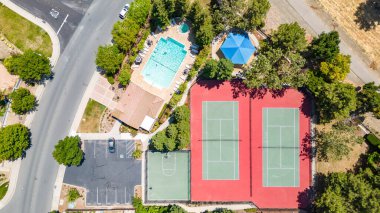 Tenis kortları, yüzme havuzu ve basketbol sahaları olan bir toplum merkezinin insansız hava aracı fotoğrafı. Konut pazarlaması için harika. 