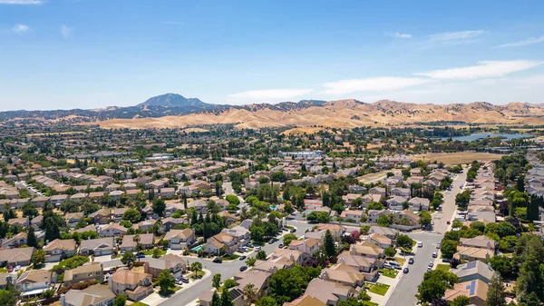 Aerial images over a community in Antioch, California with houses, cars, streets and trees. With a blue sky and room for text