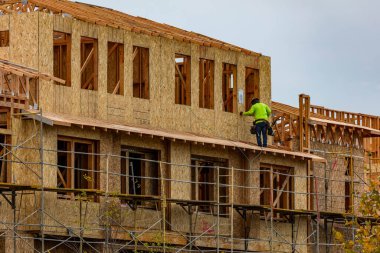 Apartman inşaatı sırasında iskelelerde çalışan bir inşaat işçisi. 